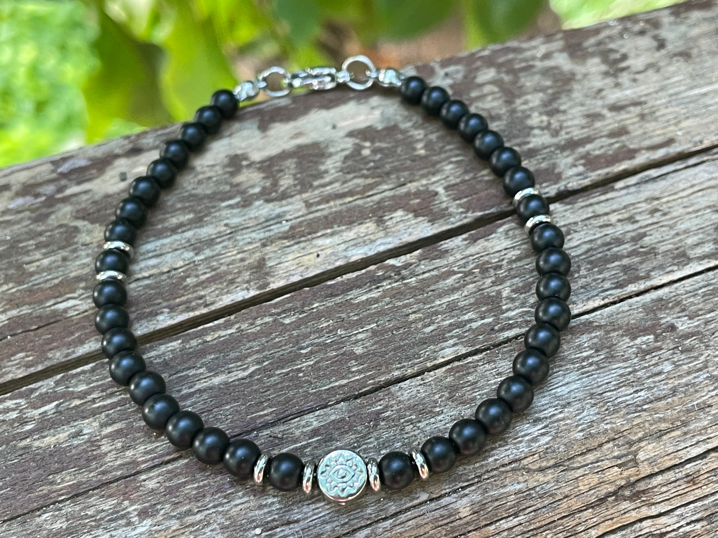 Black beaded bracelet with a silver clasp on a wooden surface