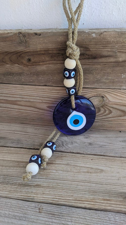 Close-up of handmade blue glass evil eye with natural rope.