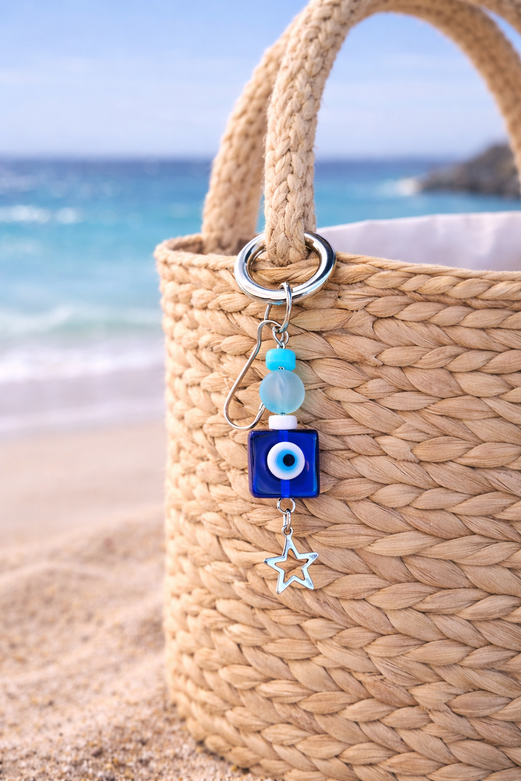 Woven bag with an evil eye keychain on a beach