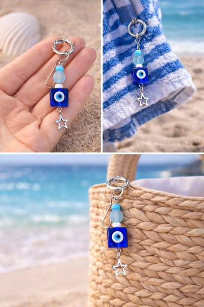 Decorative keychain with blue evil eye charm held by a hand on a beach.