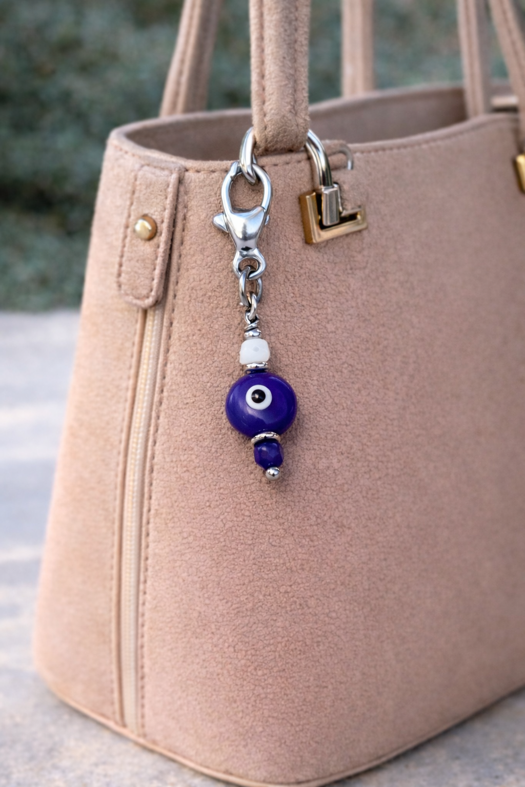 Beige handbag with a blue evil eye keychain attached