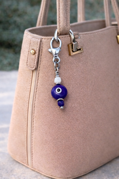 Beige handbag with a blue evil eye keychain attached