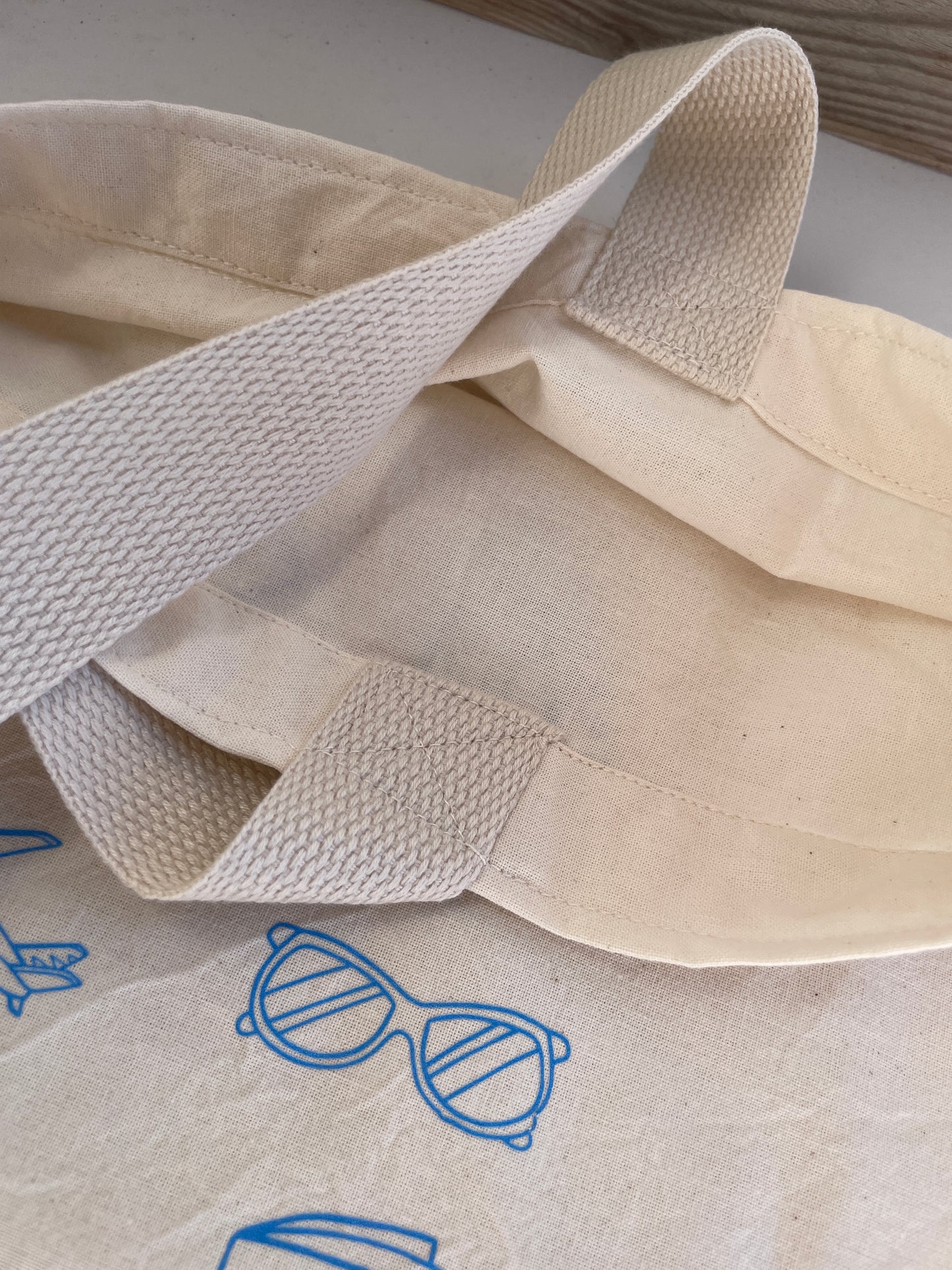 Beige fabric with a strap and blue sunglasses design on a white background