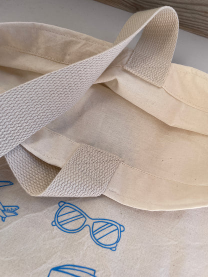 Beige fabric with a strap and blue sunglasses design on a white background