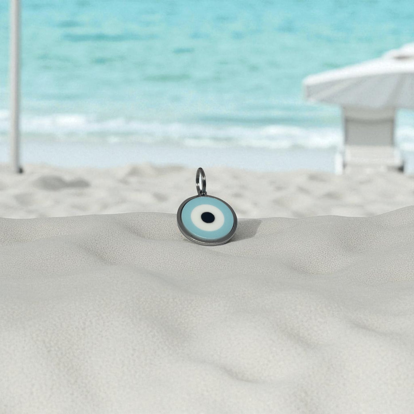 Evil eye charm on a sandy surface with a beach background