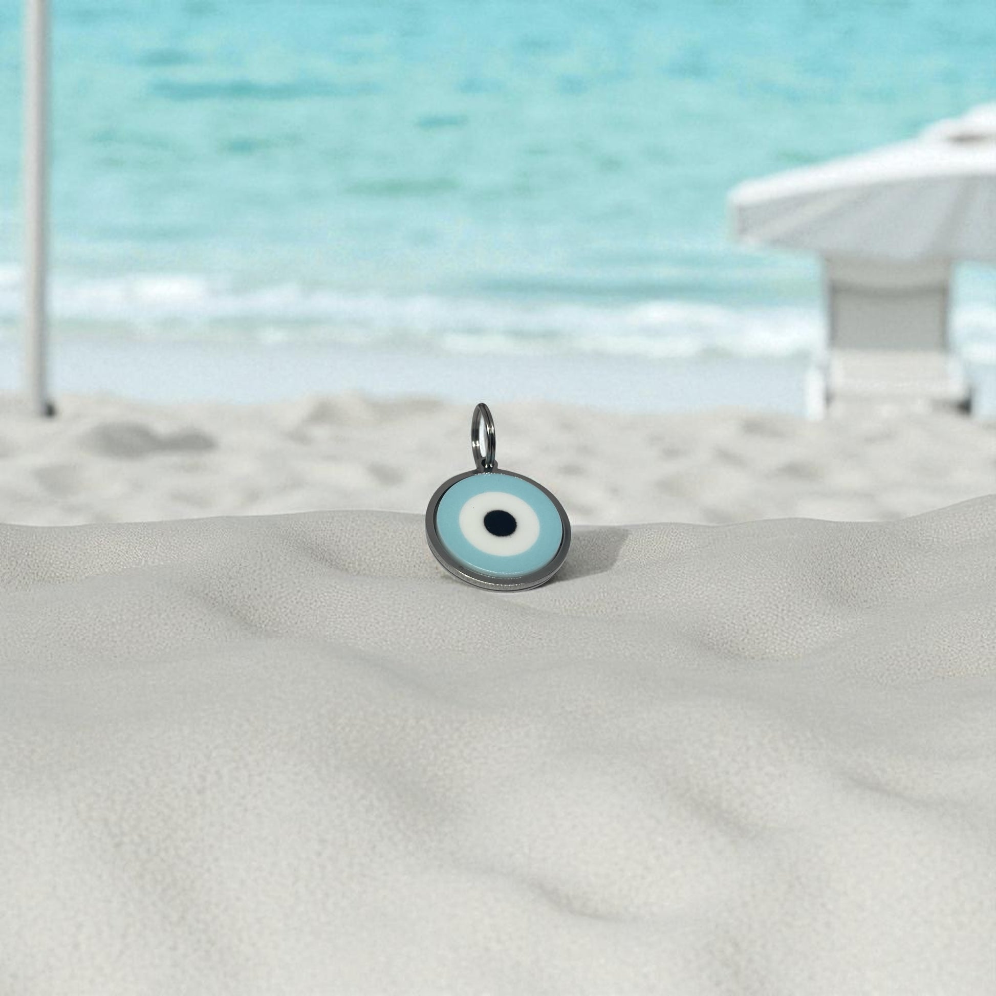 Evil eye charm on a sandy surface with a beach background