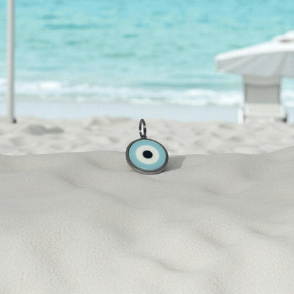 Evil eye charm on a sandy surface with a beach background