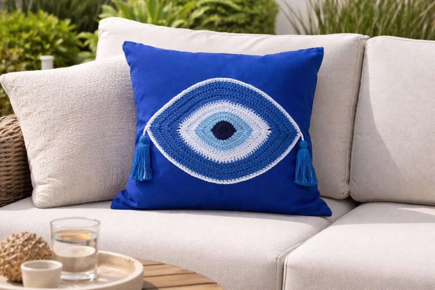 Blue decorative pillow with a eye design on a white outdoor sofa.