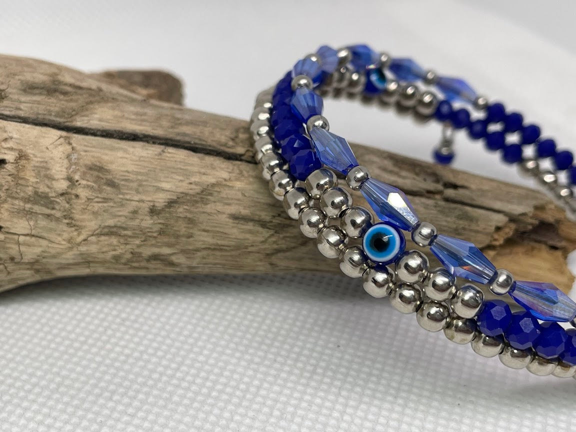 Blue and silver beaded bracelet with a blue evil eye bead on a white background