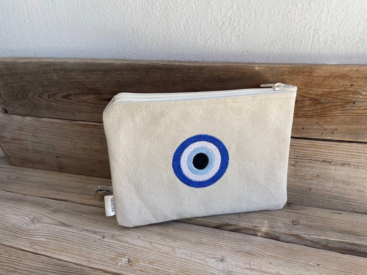 Beige pouch with a blue and white eye design on a wooden surface