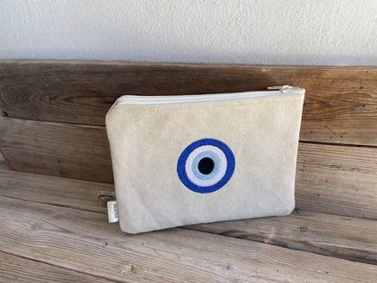 Beige pouch with a blue and white eye design on a wooden surface