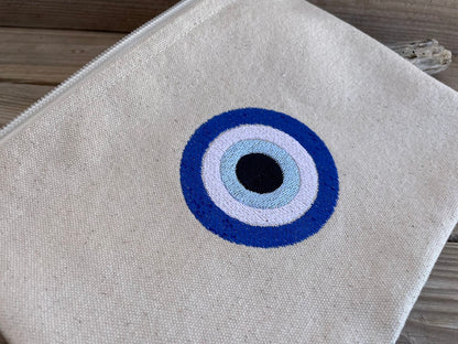 Gray pouch with a blue and white eye design on a wooden surface