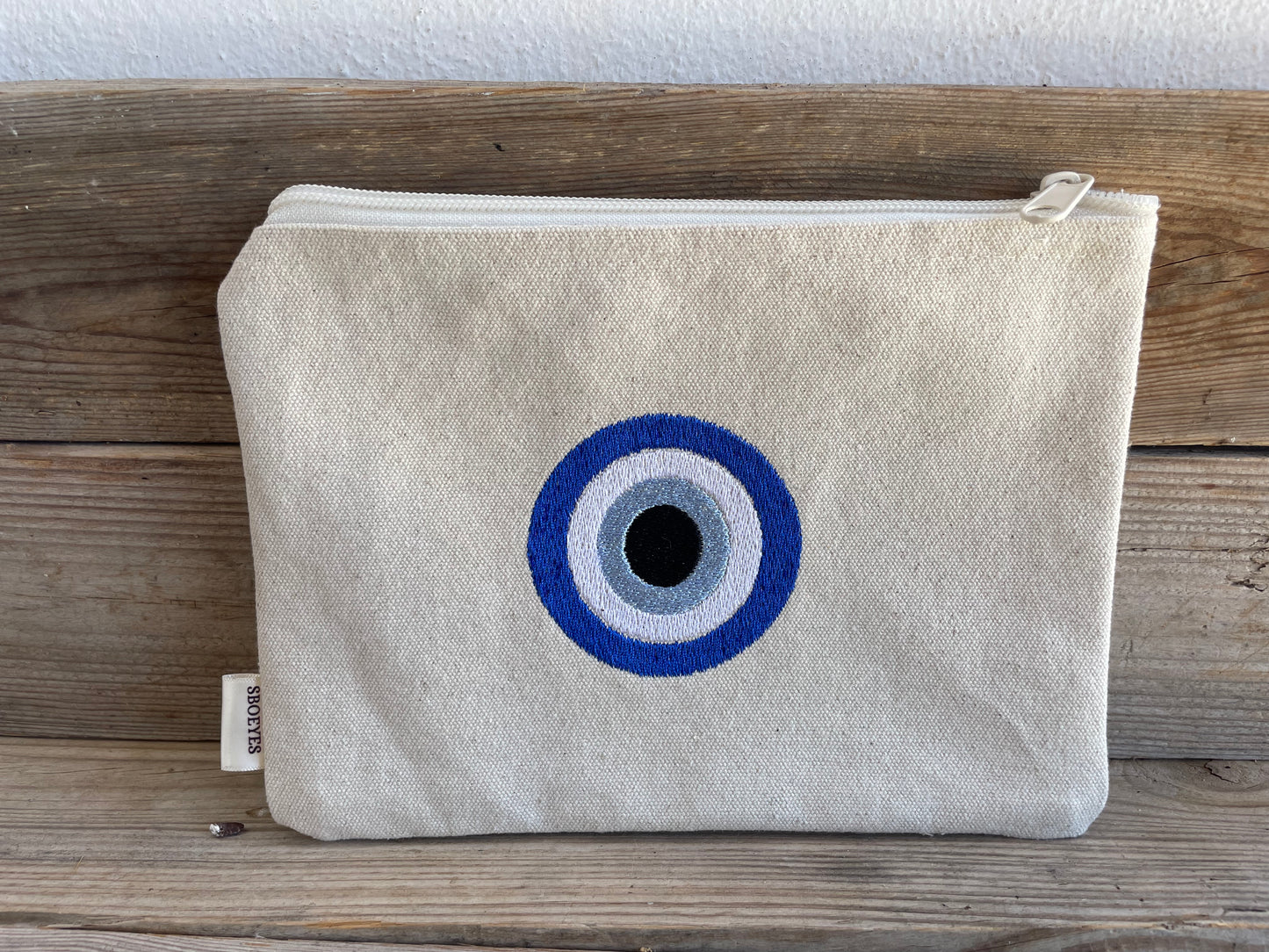 Canvas pouch with a blue and white eye design on a wooden surface