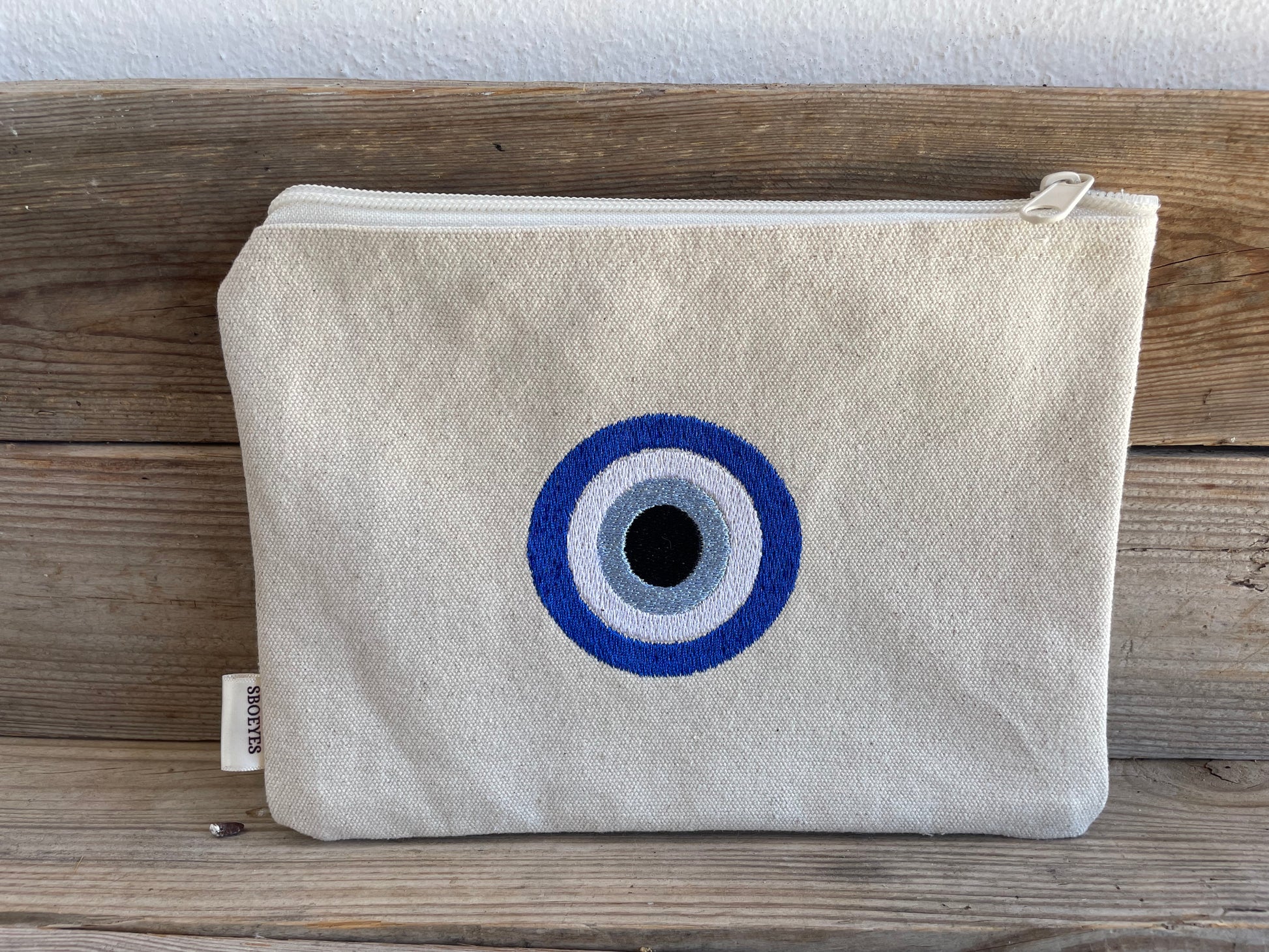 Canvas pouch with a blue and white eye design on a wooden surface