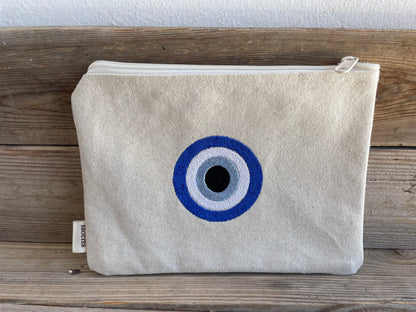 Canvas pouch with a blue and white eye design on a wooden surface