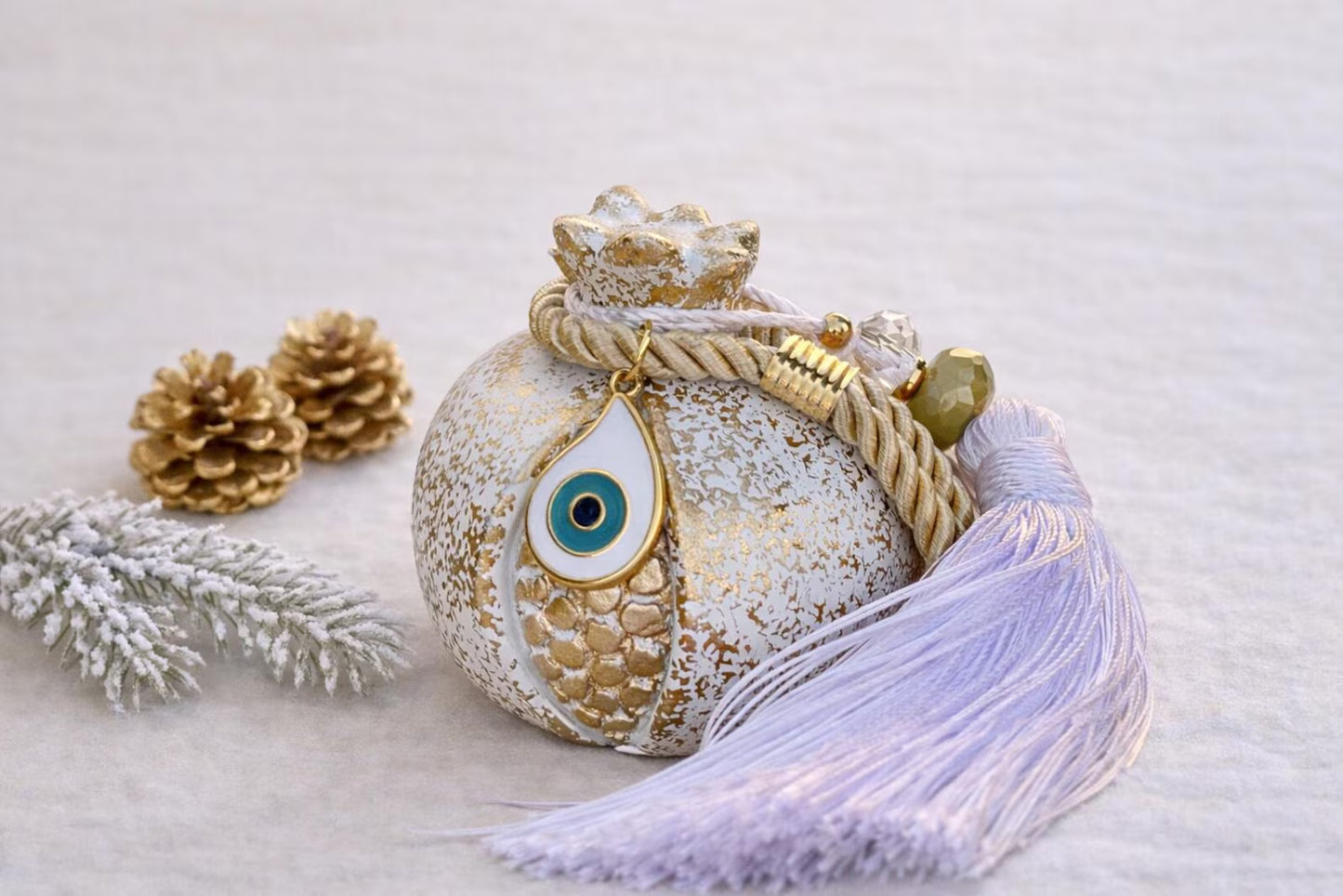 Decorative evil eye ceramic ornament with tassel on a snowy background
