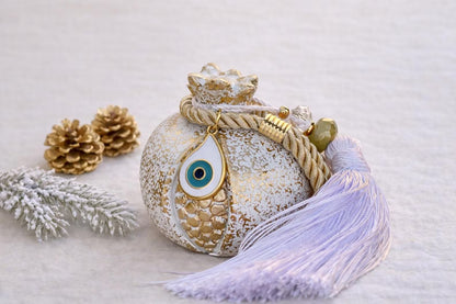 Decorative evil eye ceramic ornament with tassel on a snowy background