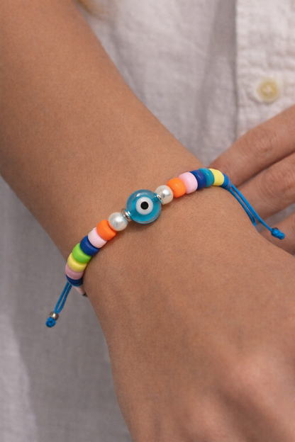 Colorful beaded bracelet with a blue evil eye charm on a wrist.