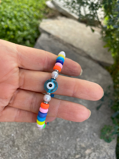 Colorful beaded bracelet held between fingers with a natural background