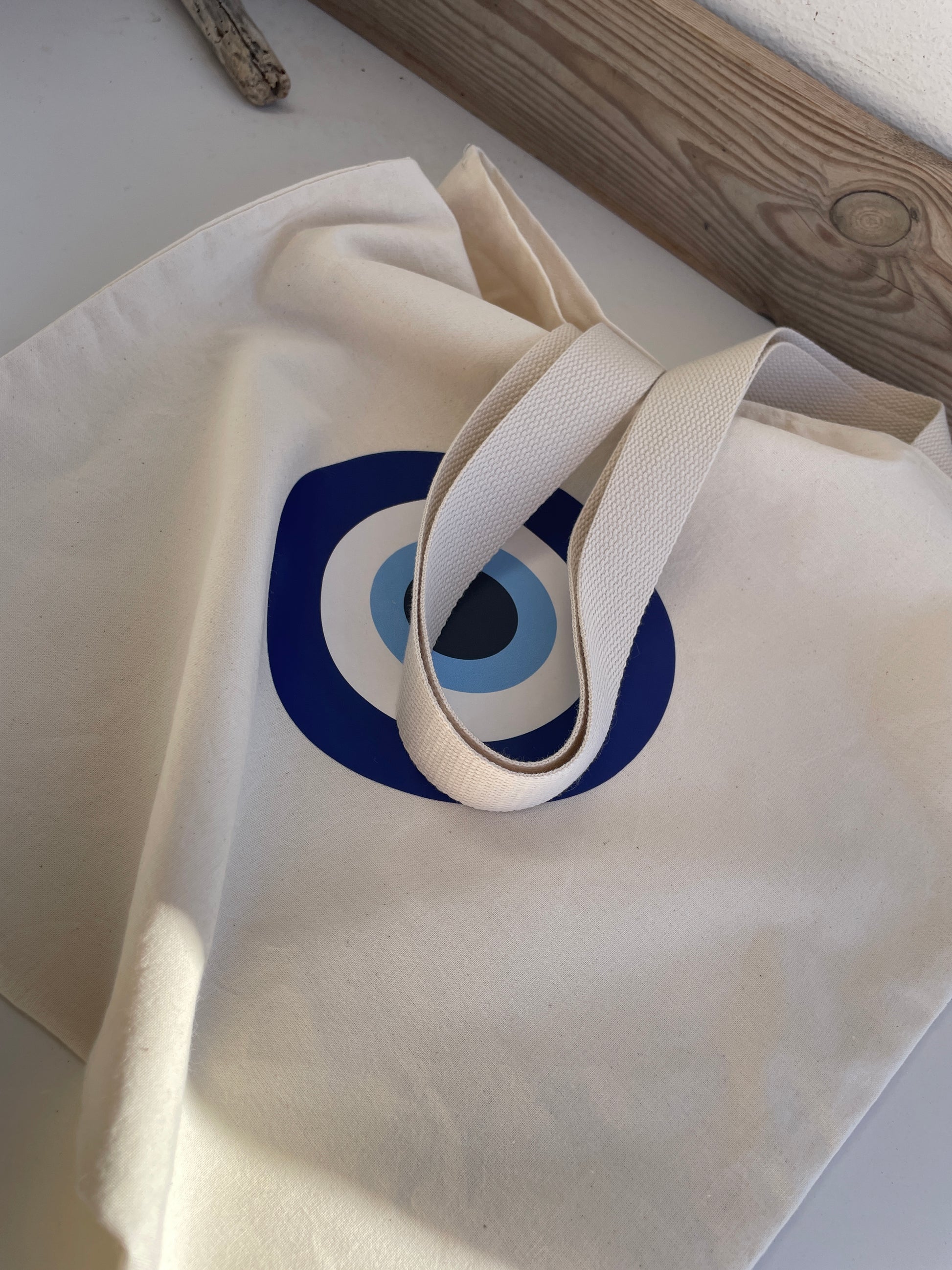 White tote bag with a blue circular logo on a light surface