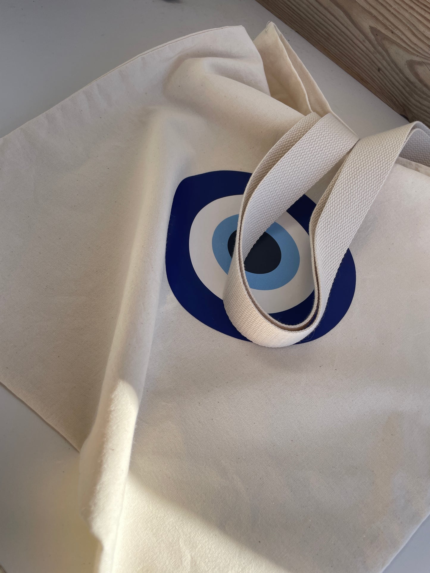 White tote bag with a blue and black circular design on a white surface.