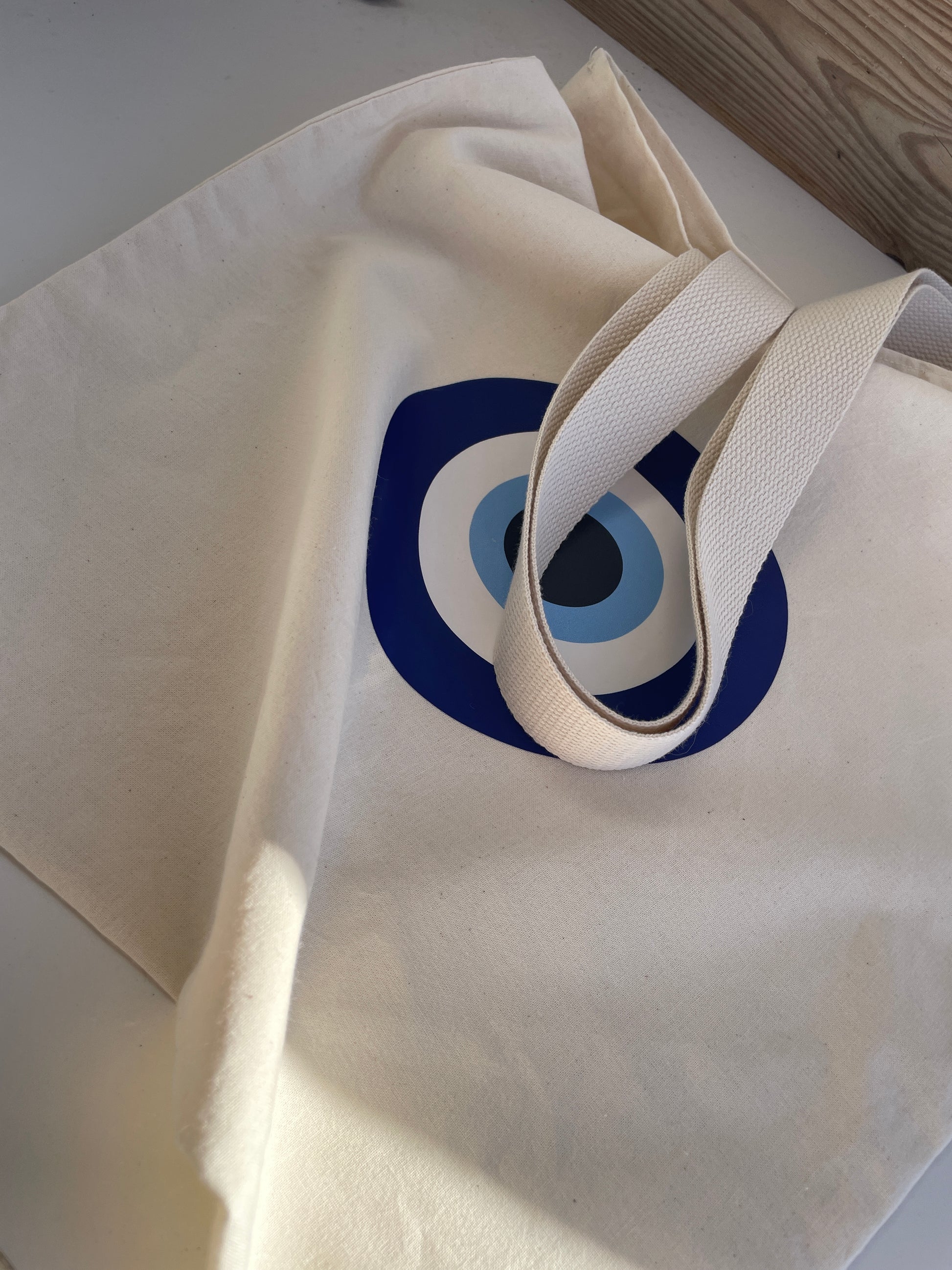 White tote bag with a blue and black circular design on a white surface.