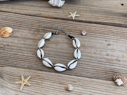 Bracelet with white shell beads on a wooden surface with starfish and shells.