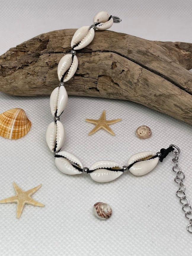 Bracelet with shell beads on a white surface with starfish and shells.