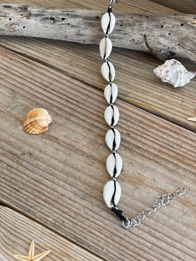 Shell bracelet on a wooden surface with shells and starfish