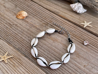 Bracelet with white shell beads on a wooden surface with shells and starfish.