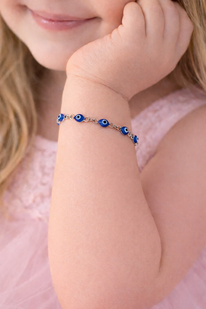 Child wearing a bracelet with blue beads on a pink background