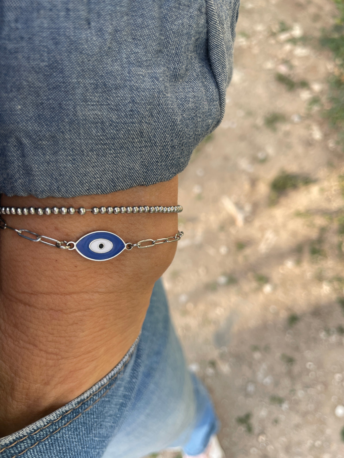 Bracelet with a blue and silver design on a wrist, with denim fabric in the background.
