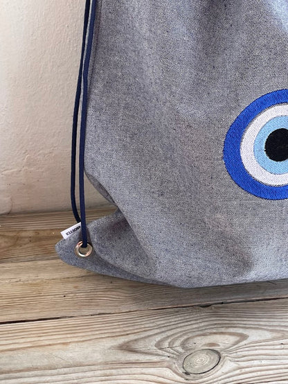 Blue-Grey Denim Drawstring Backpack with Embroidered Evil Eye