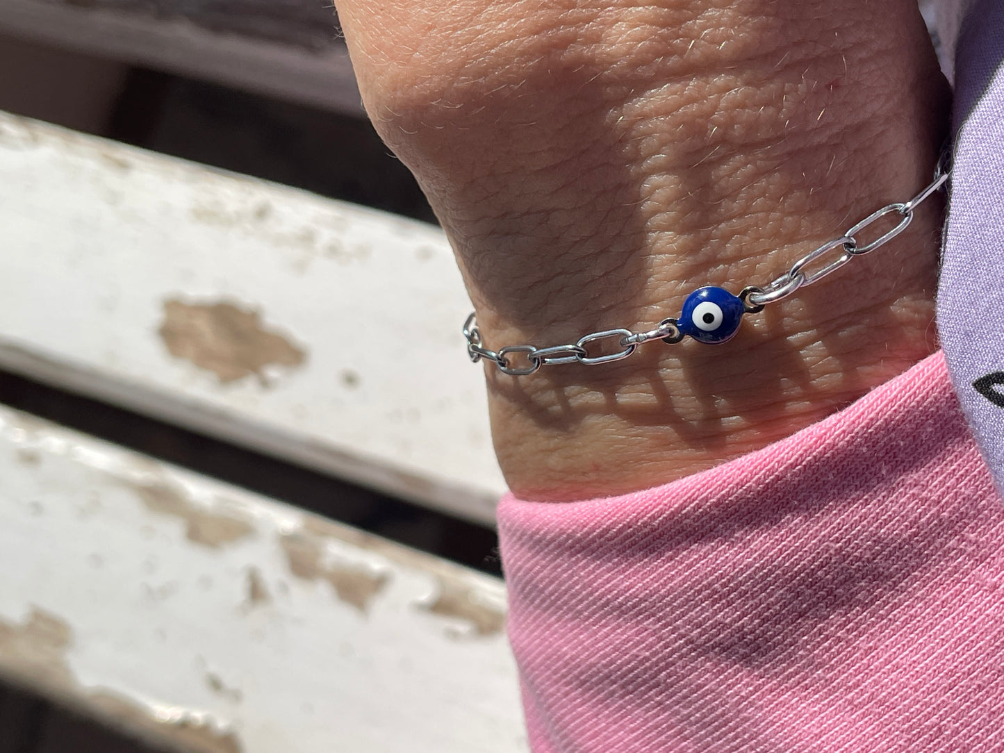Bracelet with a blue evil eye charm on a wrist, with a blurred background.