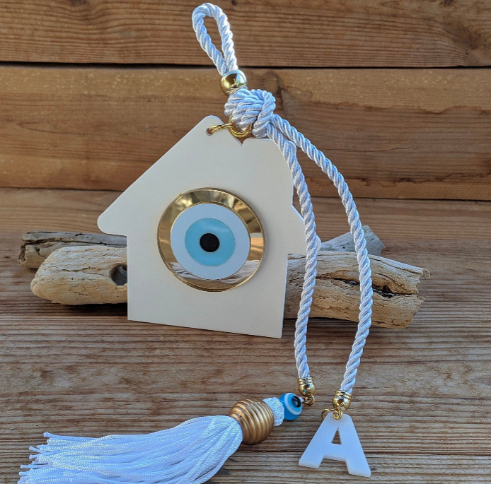 Decorative plexiglass wall hanging with evil eye symbol and tassel on a wooden background