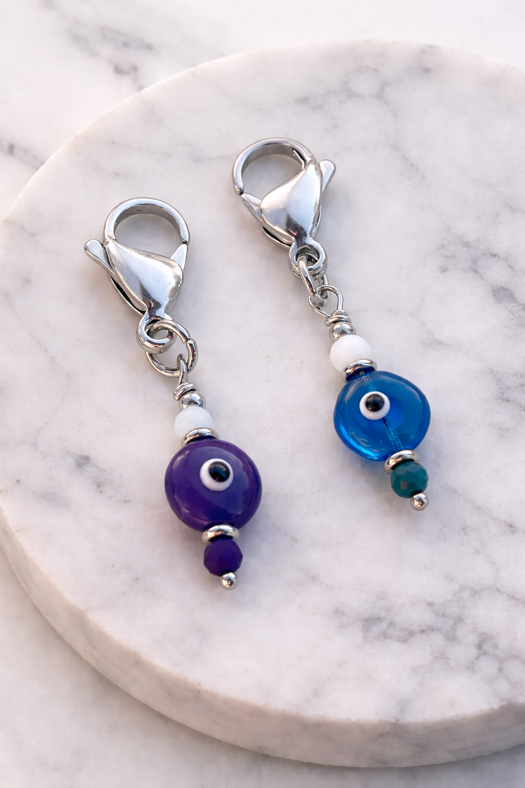 Pair of silver earrings with blue and purple beads on a marble surface