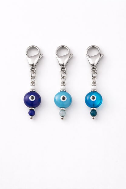Three blue evil eye charms on a white background