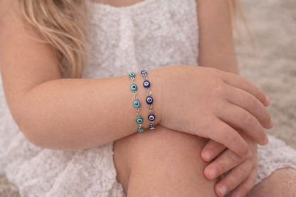 Child wearing two blue beaded bracelets on a neutral background