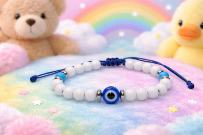 White beaded bracelet with a blue evil eye charm on a colorful background with toys.