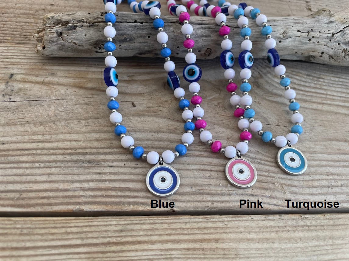 Three beaded necklaces with colorful evil eye charms on a wooden surface.