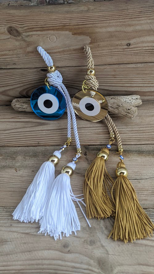 Two evil eye charms with tassels on a wooden surface