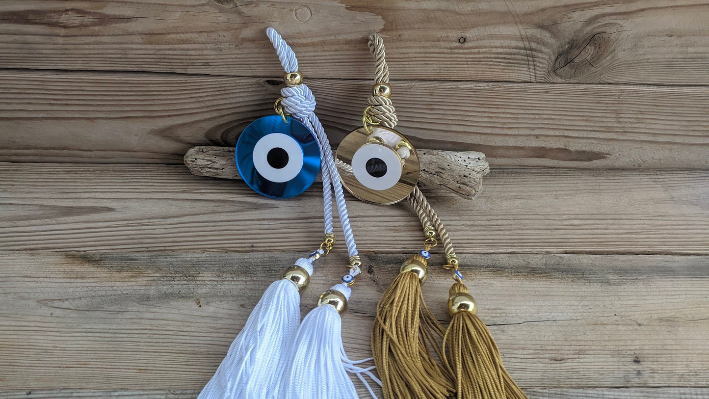 Two evil eye charms with tassels on a wooden surface