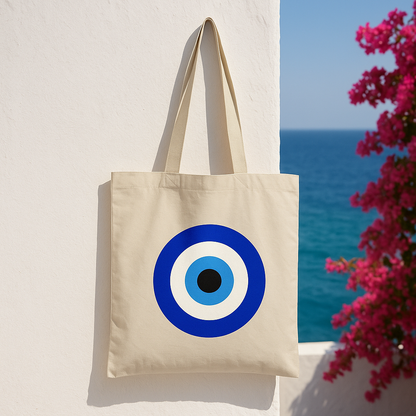 Beige tote bag with a blue and white circular design against a scenic background with ocean and flowers.