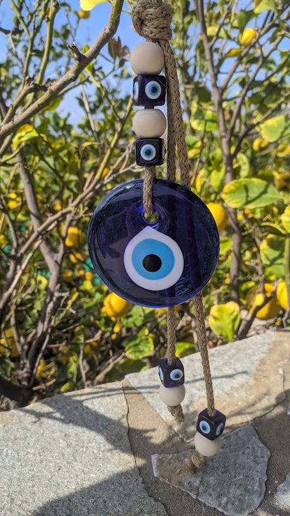 Glass evil eye wall hanging in front of a Lemon tree