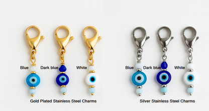Set of evil eye charms in gold, dark blue, and white on a white background.