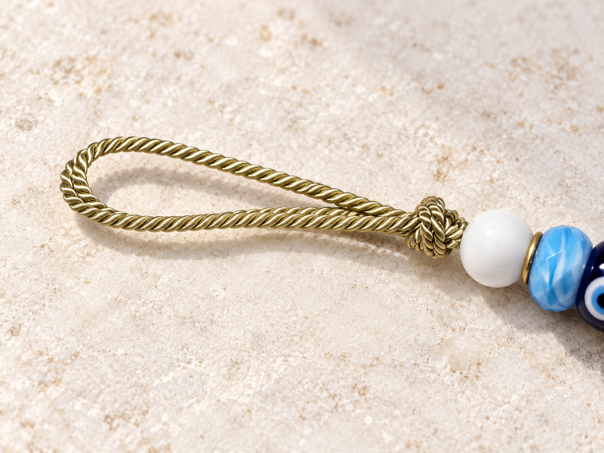 A close-up details the braided gold hanging loop of the evil eye ornament.