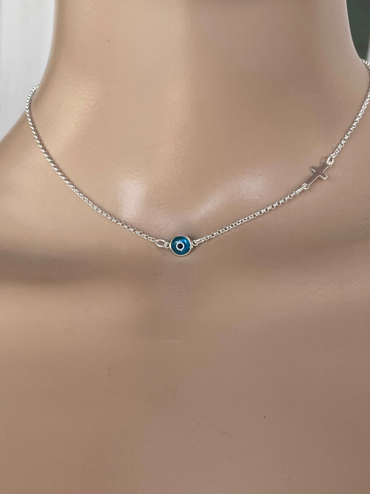 Close-up of the sterling silver evil eye cross pendant, showcasing its intricate details and polished finish.