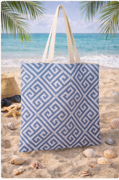 Blue and white patterned tote bag on a sandy beach with ocean and palm leaves in the background