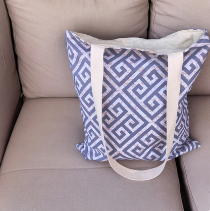 Blue and white patterned bag with beige straps on a beige couch