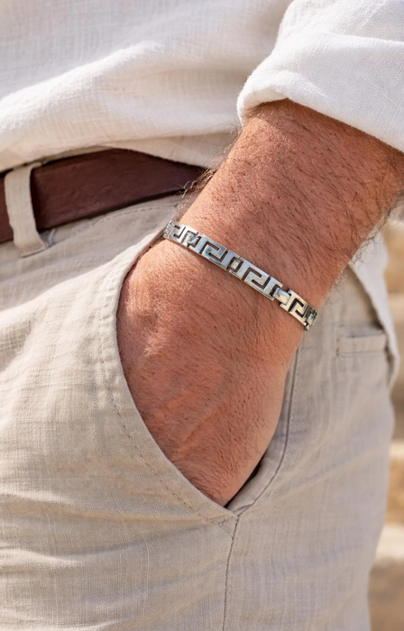 Close-up of a person wearing a silver bracelet on a wrist with a neutral background